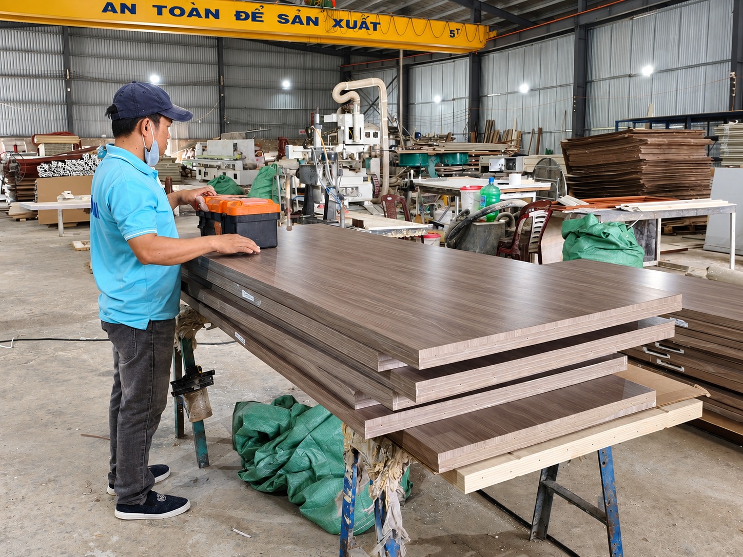 Công nhân kiểm tra bề mặt các tấm cửa vân gỗ xếp chồng tại xưởng Sumko Door