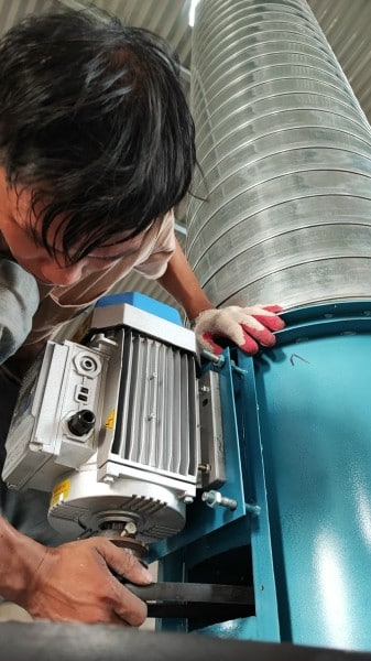 Kỹ thuật viên kiểm tra motor quạt hút trên bồn hút sơn màng nước trong quá trình bảo trì