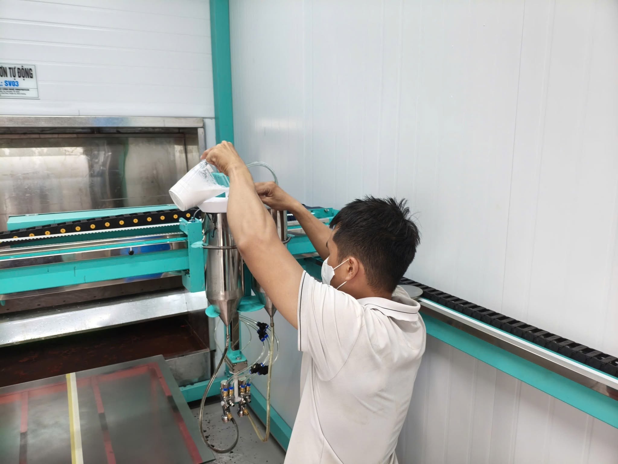 Cấp sơn vào bình chứa của máy phun sơn tự động trên kính trước khi vận hành