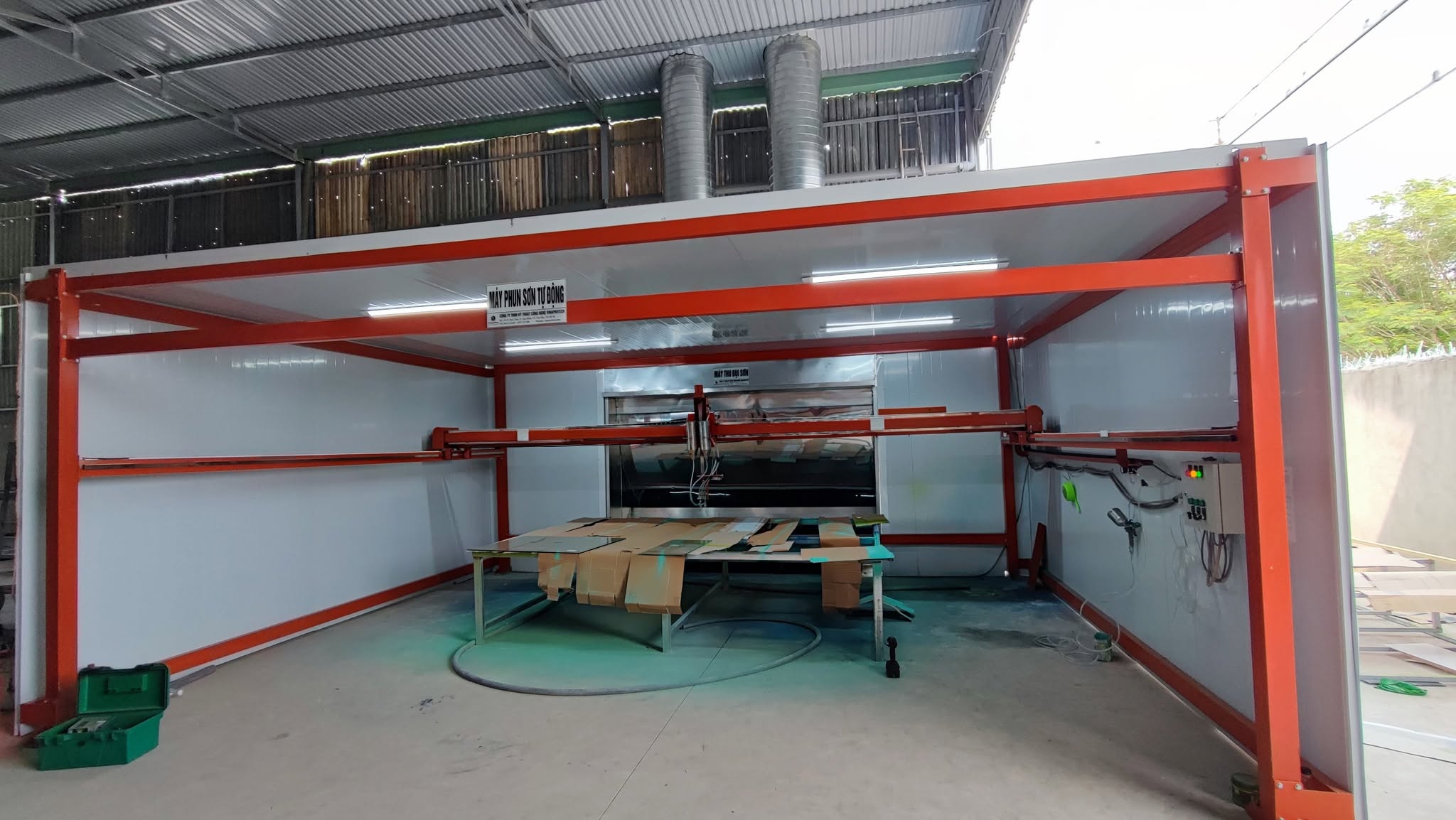 Không gian lắp máy phun sơn với khung màu cam và cụm hút phía sau